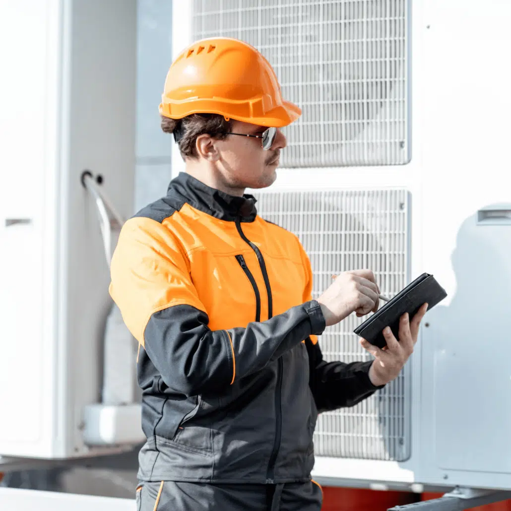 Engineer Servicing Air Conditioning Heat Pump with Digital Tablet