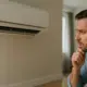 man staring at a AC unit leaking water